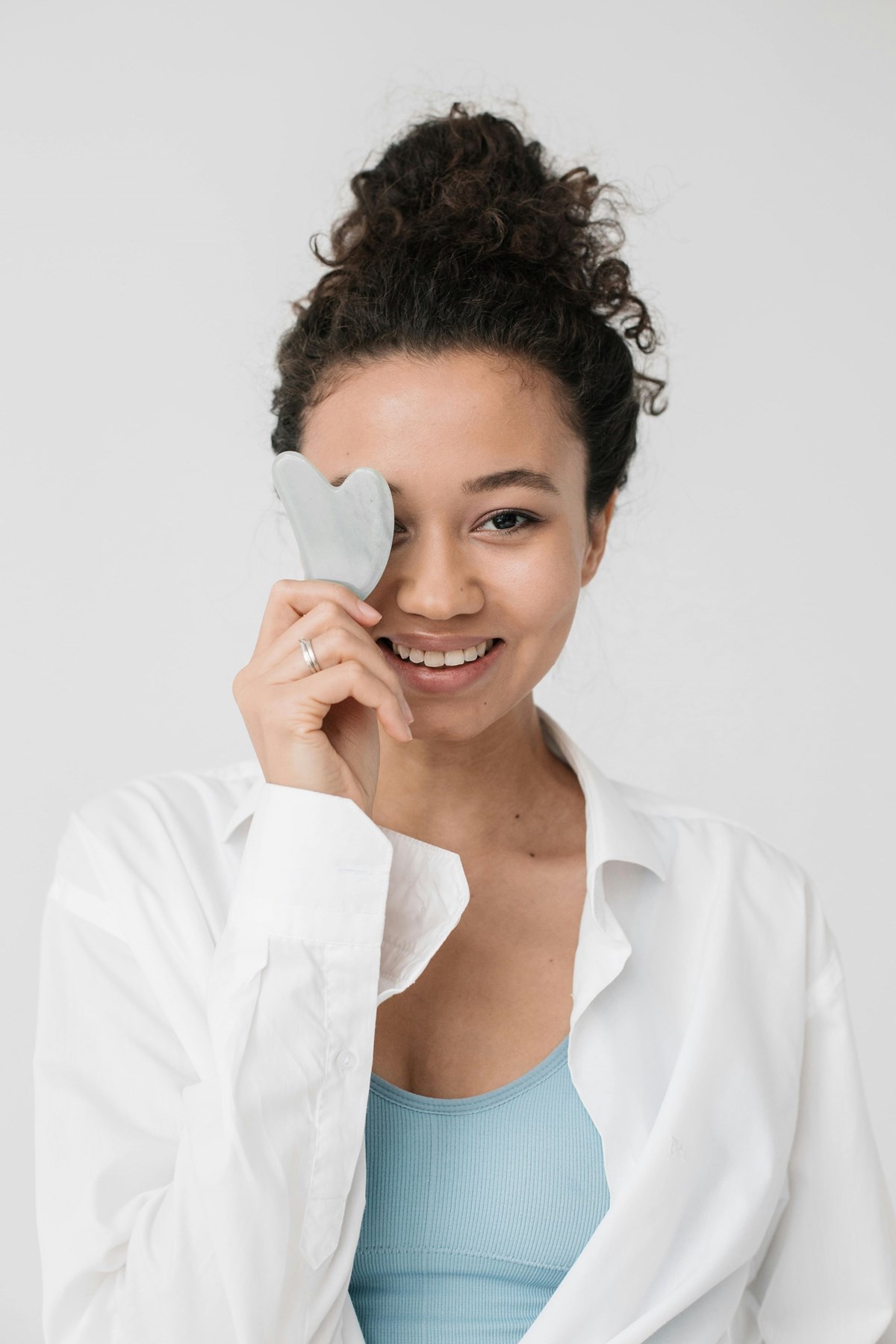 “Rose quartz Gua Sha tool with vegan serum and towel on a minimalist surface — clean beauty skincare routine.”